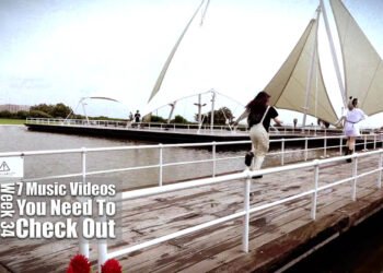 Still from BAD BABY BOMB's music video for the song "SHINE". Three members of the band BAD BABY BOMB are running over a deck near an attraction park.