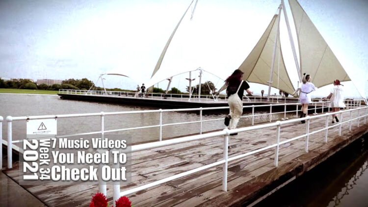 Still from BAD BABY BOMB's music video for the song "SHINE". Three members of the band BAD BABY BOMB are running over a deck near an attraction park.