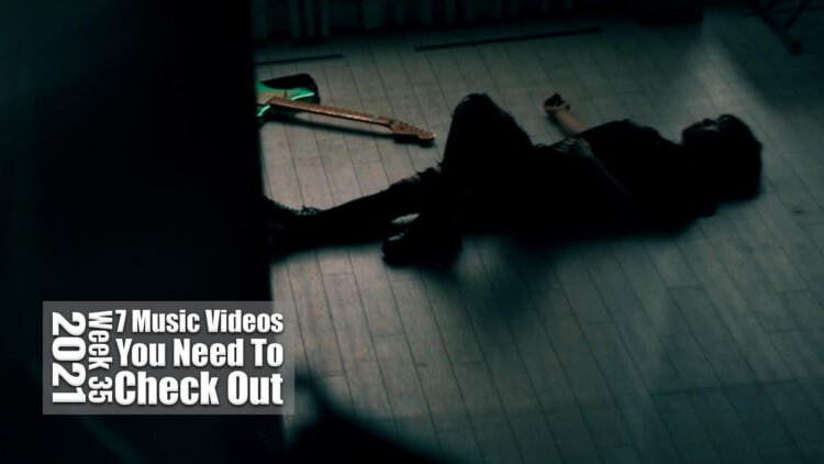 Still from Re:O's music video for the song "GUILD". The musician lies on the ground with her guitar next to her.