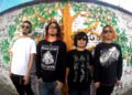 The photo shows the four members of STONE LEEK standing in front of a wall covered with graffiti. The graffiti includes a tree with green leaves and (Spanish) words. Three of the members wear black (sweat) shirts and one wears a white shirt.