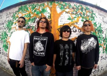 The photo shows the four members of STONE LEEK standing in front of a wall covered with graffiti. The graffiti includes a tree with green leaves and (Spanish) words. Three of the members wear black (sweat) shirts and one wears a white shirt.