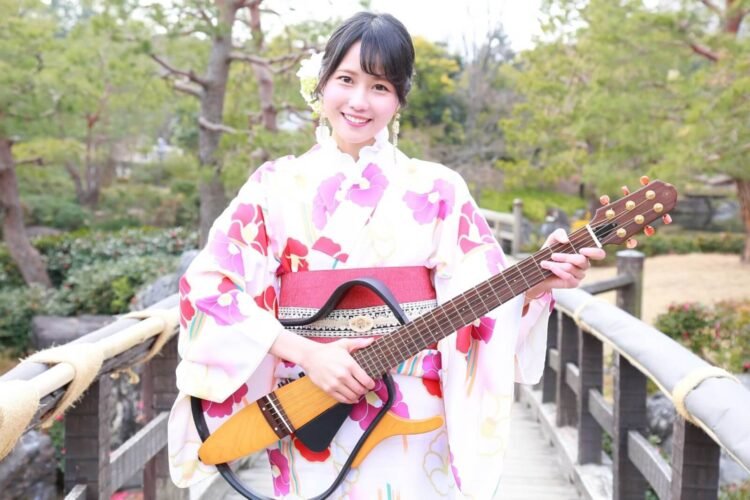 MION in a yukata holds her signature electric guitar. © MION