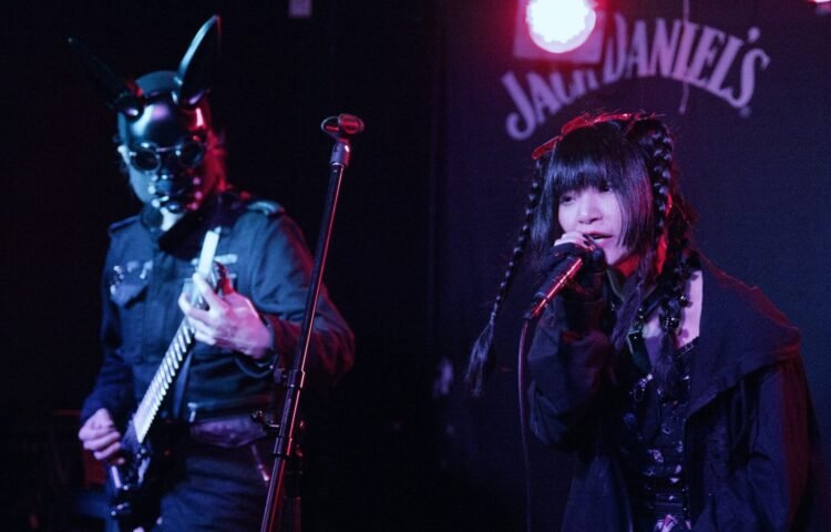 PSYDOLL at The Sunflower Lounge (Birmingham). Both members are dressed in dark clothes. One of the members of PSYDOLL is wearing a leather mask with seemingly bunny ears and plays the guitar, while the other member is singing. | Photography by James Grant (wonderlens)