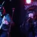 PSYDOLL at The Sunflower Lounge (Birmingham). Both members are dressed in dark clothes. One of the members of PSYDOLL is wearing a leather mask with seemingly bunny ears and plays the guitar, while the other member is singing. | Photography by James Grant (wonderlens)