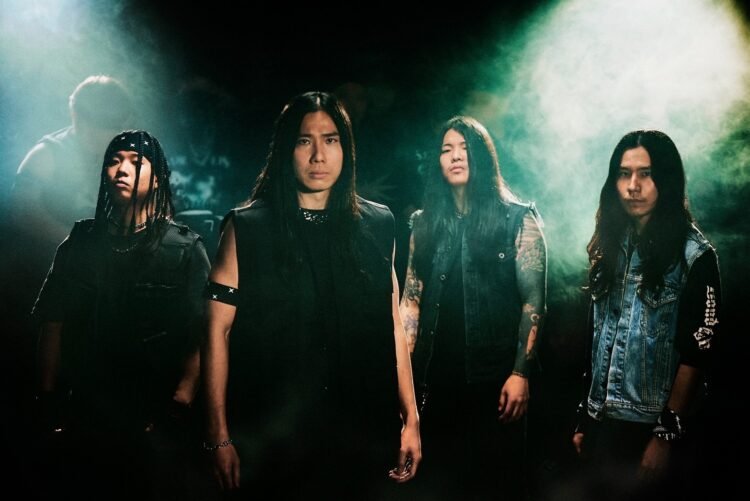 The four members of Sable Hills, dressed in dark clothes, pose in front of an apparent audience, lights are shone on them from behind so that they are very clear in the picture. © SABLE HILLS