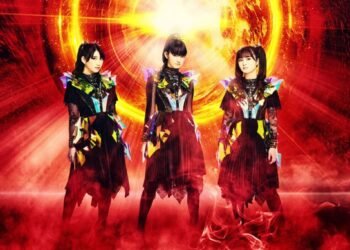 The three members of BABYMETAL are posing while being surrounded of what looks like fire.