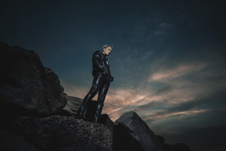 Miyavi dressed in black leather is standing on a rock formation.