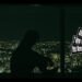 Still from the music video by the band kao for the song "New era". The still features a night view of a city and a shadow of a person that is sitting down.
