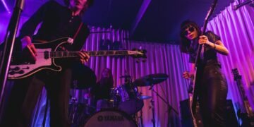 An action photo of The Highmarts on stage with bassist Atsushi in front and guitarist and vocalist Suzu and drummer Minako in the background. The photo was taken in March 2023, during a show organised by the band itself at Shimokitazawa Live Haus.
