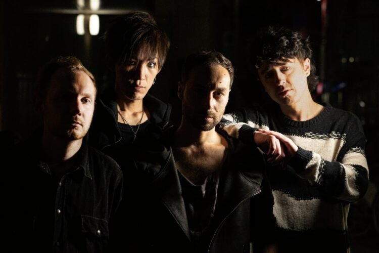 The four current members of ASK I FALL (in 2023) posing a dark area with limited light sources allowing the faces of the band members to be visible on one side.