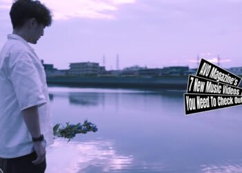 Still from MIKENN's music video for the song "瞬き (Blink)". A man with dark pants and a white shirt stands near a river with a small bouquet with the idea to throw it into the water.