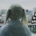 Still from SOM4LI's music video for the song "メイ (Mei)". A person is wearing a bunny hat and looks out from the balcony to the city and public transport.