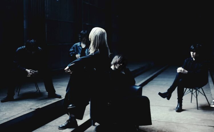 Band photo of the Japanese alternative rock/shoegaze band BLOOD PICK ME. The band members of BLOOD PICK ME are sitting scattered on chairs in a dark corner of an abandoned venue. The band members are all dressed in dark clothing, making them almost disappear due to the lack of light.
