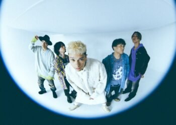 Band photo of the five-piece coldrain made with what seems a fisheye lens. The band members are standing next to each other, some band members look away, the vocalist Masato, who stands in the middle, leans forward towards the camera lens. Photo by Yao Lange