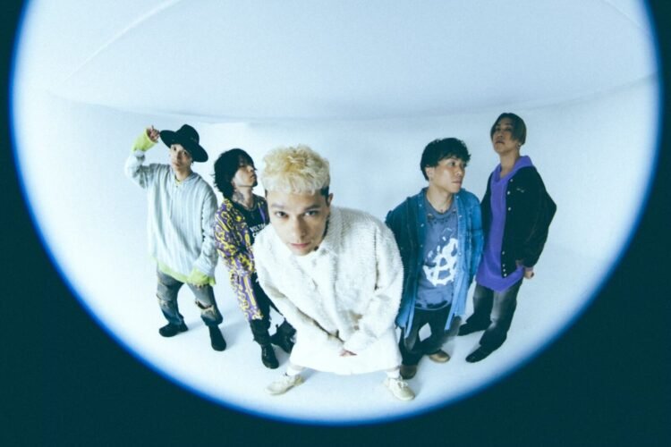 Band photo of the five-piece coldrain made with what seems a fisheye lens. The band members are standing next to each other, some band members look away, the vocalist Masato, who stands in the middle, leans forward towards the camera lens. Photo by Yao Lange