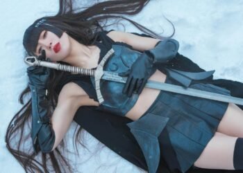 The photo depicts Himari Tsukishiro lying on a snowy surface, while being equipped with a sword and is clad in an outfit that includes a black leather dress and an the top part of her outfit has been decorated with an armour-like component. Her long black hair is spread out behind her, and she has red lipstick on. She is also wearing black gloves and a black headpiece that features a spikes. The environment around her is a serene, snow-covered expanse. The photo has been used as a cover for the single 浄​土​独​唱 (Jodo Dokushou), released in April 2023.
