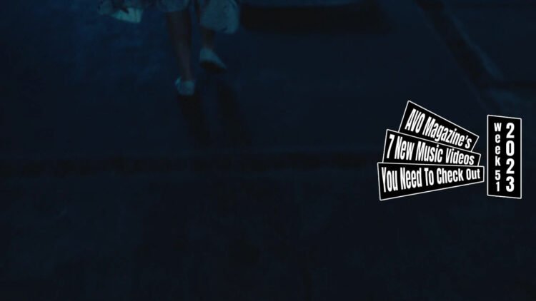 Still from the music video for "Hameln" by the band 灰かぶり (The Cinder). The still shows one of the dancers in the music video wearing white shoes and a white dress with colourful marks made by paint as she walks away from the screen and the camera is pointed at the floor. The surroundings of this location looks very dark.