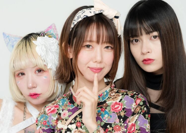 From left to right: Nonayu, Miho, and Okinawa Electric Girl Saya The image shows Nonayu, Miho, and Okinawa Electric Girl Saya standing together, each showcasing her individual style. Nonayu is dressed in white clothing, while Okinawa Electric Girl Saya is dressed in black clothing. In the middle, Miho, is dressed in a colourful dress, seemingly a qipao (Chinese traditional dress).