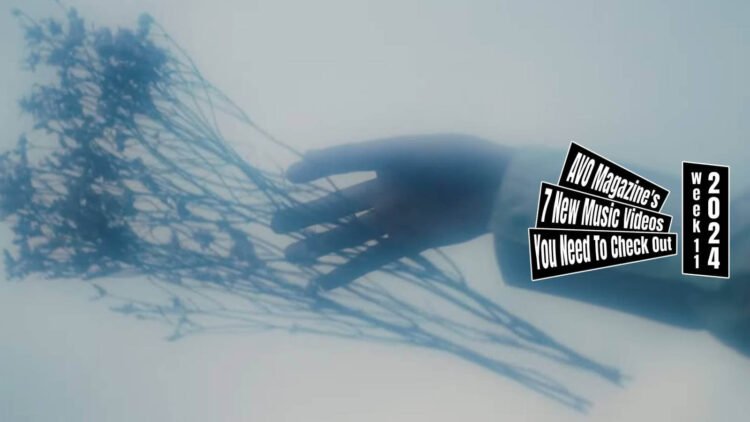 Still from Plums' music video for the song "生活 (Seikatsu)". The still shows an outstretched hand in a white sleeve against a white background with a dreamlike, hazy atmosphere. The hand is letting goew of a what seems to be a some herb branches.