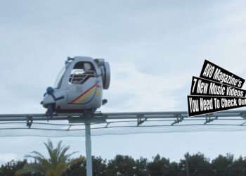 Still from the music video by おとなりにぎんが計画 (Otonari Ni Ginga Keikaku) for the song "ピアスを外して (Pierce wo Hazushite)". A girl is in what seems to be a children's amusement park and sitting in a cart on rails that you can bring forward by pedalling. The still also shows cloudy weather and the top of some trees, because the cart is on quite some height.
