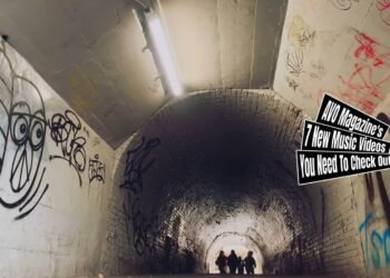 Still from the music video "Monster" by yummy'g. The musicians of yummy'g are running through a tunnel that is covered with graffiti, at the moment of the still they are still at the beginning of the tunnel.