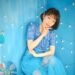 In this photo, Yukka is dressed in a blue outfit and seated in a blue-themed room, sitting on a blue bench with her right hand supporting her head while her other arm is resting on her left leg. Photo by Gentoku Ishii