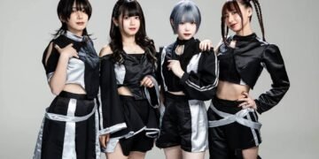 The photo features the four members of Broken By The Scream standing shoulder to shoulder against a light background. They are wearing coordinating black and silver costumes and each having a unique hairstyle.