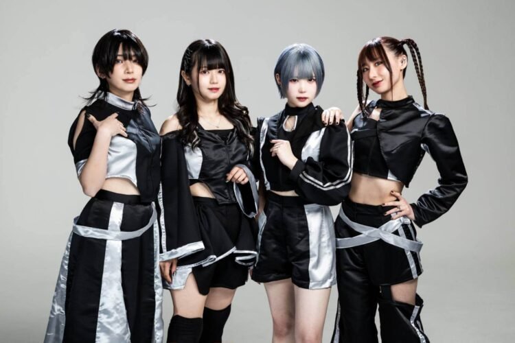 The photo features the four members of Broken By The Scream standing shoulder to shoulder against a light background. They are wearing coordinating black and silver costumes and each having a unique hairstyle.