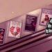 Still from the music video "FRIDAY" by the trio QUINCAMPOIX. The still captures a scene inside a subway, featuring a flight of escalator stairs. Along these escalator stairs, a series of posters with various messages and advertisements are mounted on the wall.