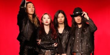 The photo depicts THE STEREOGANG consisting of four members, posing against a vivid red background. Each member is dressed in black (leather) attire.