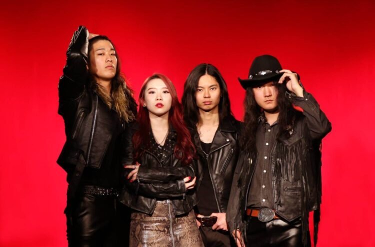 The photo depicts THE STEREOGANG consisting of four members, posing against a vivid red background. Each member is dressed in black (leather) attire.