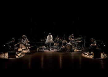 goat on stage in 2023. It features the five members of goat engaging in a performance while sitting in a semicircle setting. Photo: Yoshikazu Inoue