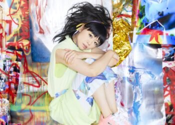 The photo depicts the Japanese pianist and jazz composer Hiromi Uehara, also known as Hiromi, wearing a colourful outfit (light green with white and blue/purple elements) with her arms crossed and resting on her knees and her head tilted and looking towards the camera, almost giving the idea that her head is supported by her arms. The backdrop consists of a combination of paintings, colourful grafitti and foil. The photo was used for the promotion of her latest album, "Sonicwonderland". © Yamaha Music Entertainment Holdings, Inc.