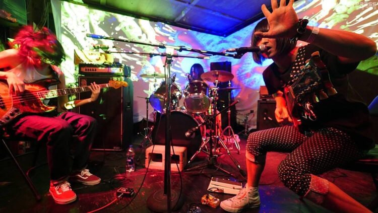 An action shot of the three members of Green Milk from the Planet Orange in the middle of a performance taken in 2019.