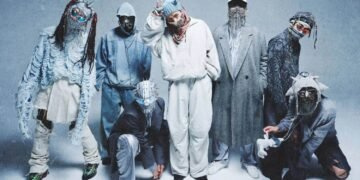 The photo features a group of seven individuals that are part of MILLENNIUM PARADE. The members are all alight in various poses and outfits, in the centre is Daiki Tsuneta, he is the only one where his eyes is not obscured.