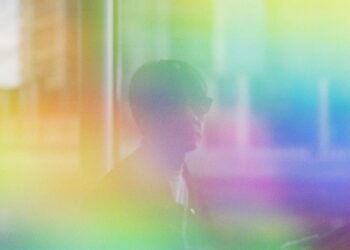 Portrait photo of Cornelius with sunglasses and on top of that a colourful filter with yellow, orange, green, blue and purple, creating a dreamy, hazy atsmosphere.