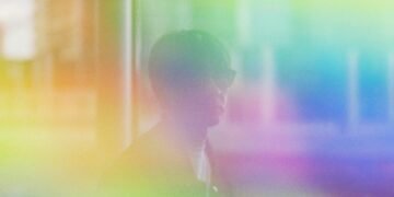 Portrait photo of Cornelius with sunglasses and on top of that a colourful filter with yellow, orange, green, blue and purple, creating a dreamy, hazy atsmosphere.