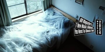 Still of the music video "eureka" by the band bakeru.., directed by Mei Kawaguchi. The still depicts a bedroom featuring a bed decorated with sheer sheets/curtains. To the right is a wall with photo frames and paper memorandums and on the left is a window with a view to a garden.