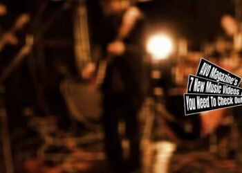 Still from the music video for "むくろに訊け (Mukuro ni kike)" by shelives(in kyoto). It is a fade out of the performing band after finishing the song, the focus disappears, making the band members look blurred. The stage they perform at is dark but illuminated by a few stage lights.
