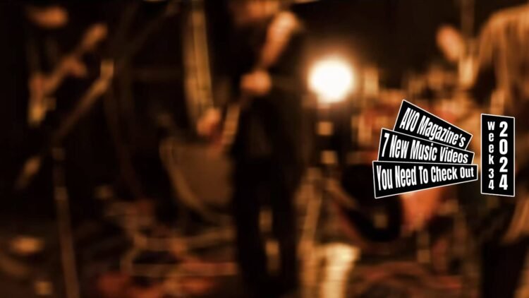 Still from the music video for "むくろに訊け (Mukuro ni kike)" by shelives(in kyoto). It is a fade out of the performing band after finishing the song, the focus disappears, making the band members look blurred. The stage they perform at is dark but illuminated by a few stage lights.
