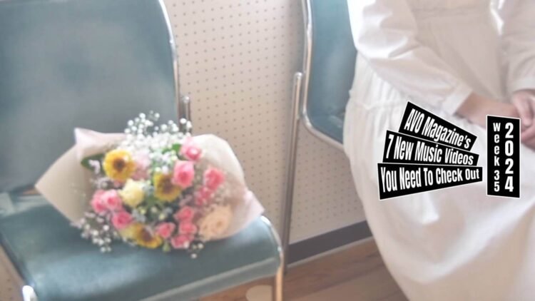 Still from April After All's music video for the song "march". A lady dressed in a white dress is sitting on a green chair and next to her is a bouquet of colourful flowers. They are sitting next to a window that gives a lot of light and creates a hazy atmosphere as it the camera is overexposed. The filming and editing is done by one of the members of the band, Muneda.