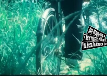 Still from mogari's music video for "春がそうさせる (Spring makes me do it)", which is directed and filmed by シタンダリンタ (@ndarinta). The still shows of one of the band members of mogari cycling his bike through the high grass. The editing gives a tranquil and nostalgic atmosphere, especially with the effect as if you are looking through a vintage film reel.