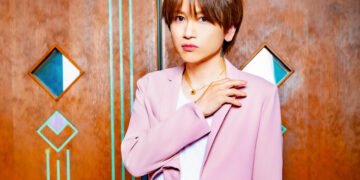 An Cafe's Miku posing in a light/old pink suit against a wooden wall.