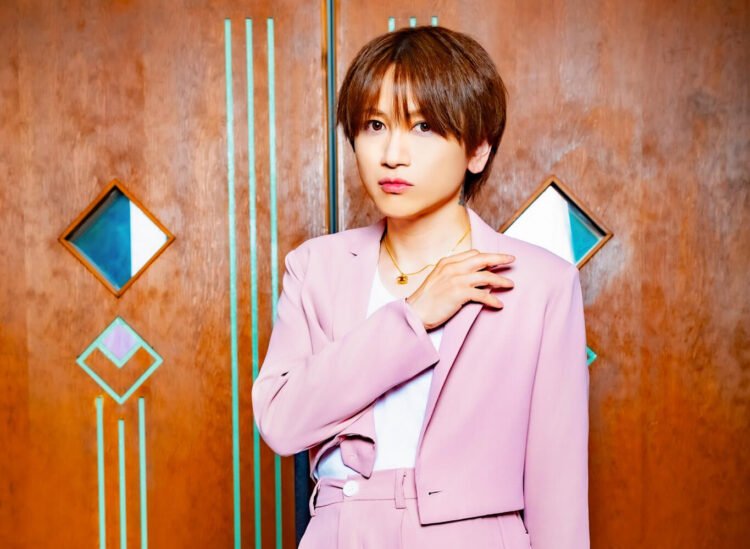 An Cafe's Miku posing in a light/old pink suit against a wooden wall.