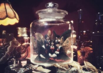 The photo displays an eerie and mysterious collection arranged on a table, including a glass jar with the members of Phantom Siita. This photos is used in the promotion for the Moth To A Flame world tour. © Cloud Nine inc.
