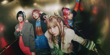 The photo shows the four members of HANABIE. posing together in an elevator. Each band member is distinctly dressed in colourful and unique outfits. From left to right: drummer Chika, guitarist/vocalist Matsuri, vocalist Yukina, and bassist Hettsu.