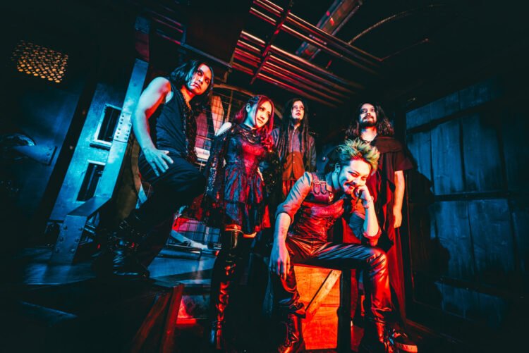 The photo depicts the (support) members of FATHOMLESS SKYWALKER dressed in a gothic-inspired metal style in a dark lit room, probably located in an (old) factory with red lighting to amplify the atmosphere. Photo by Ato4 Sound Factory (@ato4soundfactory)
