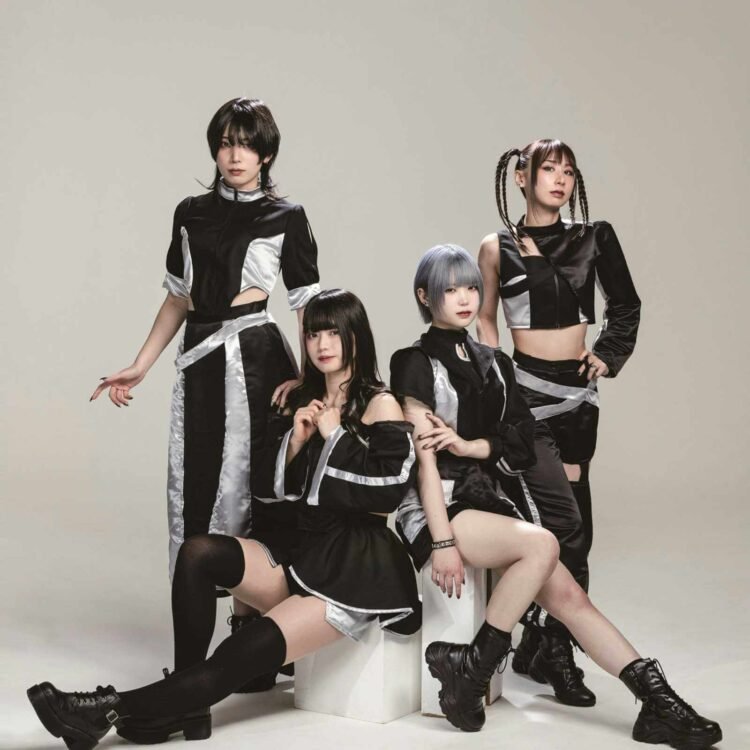The photo features the four members of Broken By The Scream posing against a light background, two of the members are sitting on white blocks, while the other two are standing behind them. They are wearing coordinating black and silver costumes and each having a unique hairstyle.