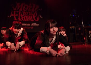 The photo depicts a moment in Phantom Siita's performance during their show in London. The five members are on stage, dressed in the same costums and kneeling on the ground while leaning forward and placing the pointing fingers on the ground. Photography by JJ Grant (Wonderlens)