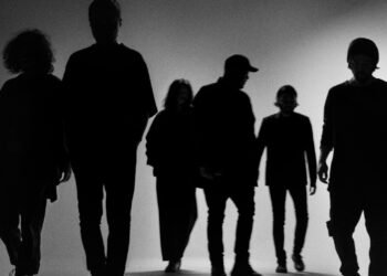 The (monochrome) photo shows the silhouettes of the six band members of envy standing in a row, walking forward.
